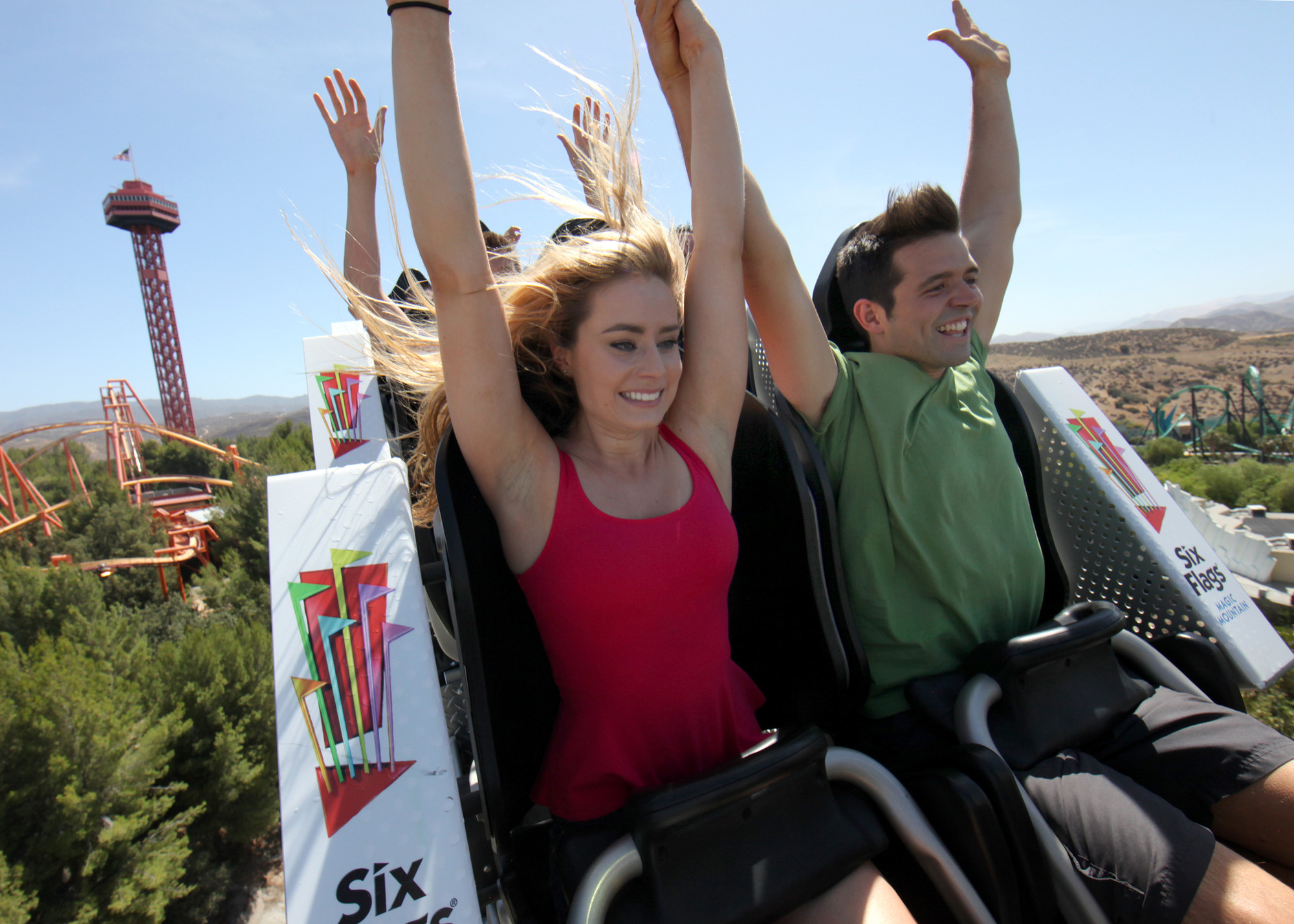 People on a roller coaster with their hands in the air
